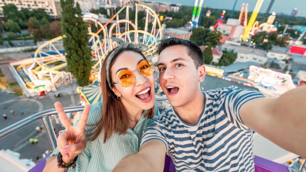 Loving mixed race couple hugging and riding on the Ferris wheel and take a selfie photo during the weekend at the amusement Park. Date and relationship