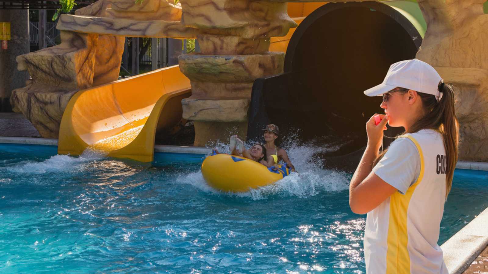 A lifeguard girl watches people having fun in a water park.