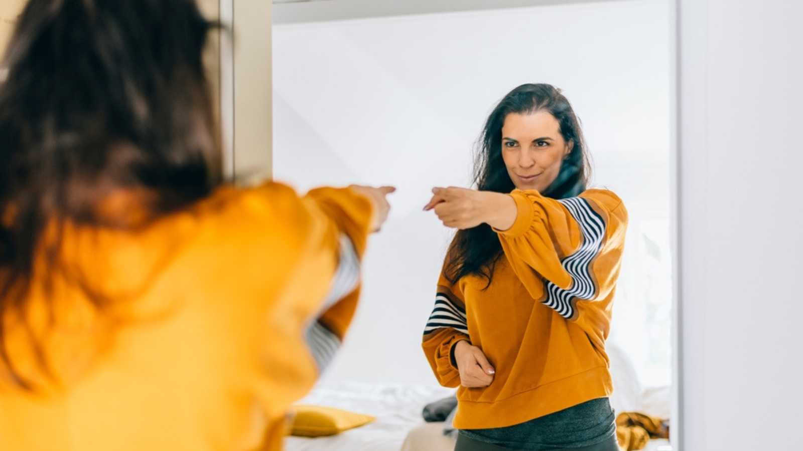 Woman pointing hands at her in mirror