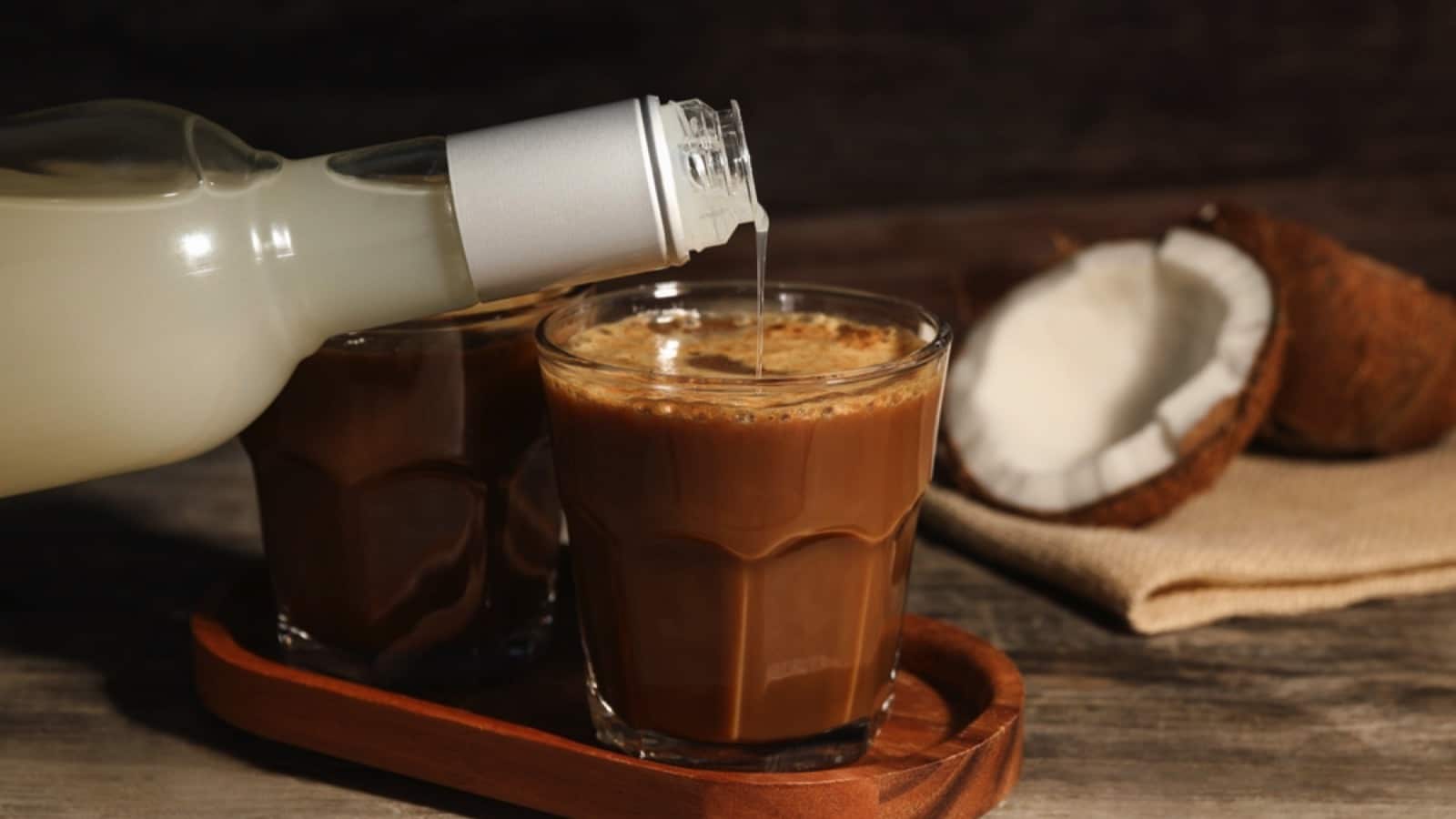 Pouring coconut syrup into glass with tasty coffee